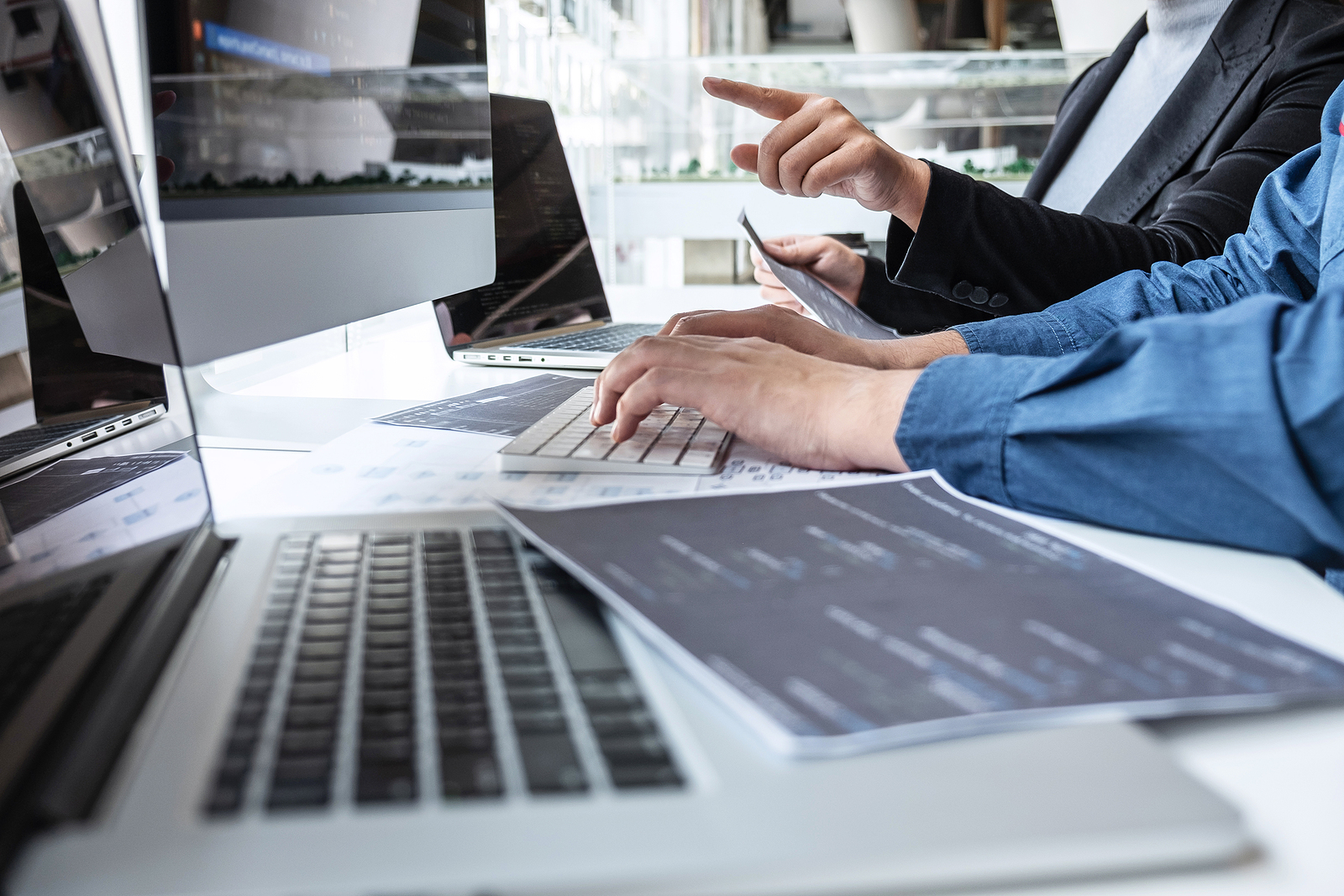 Developers collaborating at computers in a modern workspace, representing tech PEO digital onboarding and multi-jurisdiction payroll support.