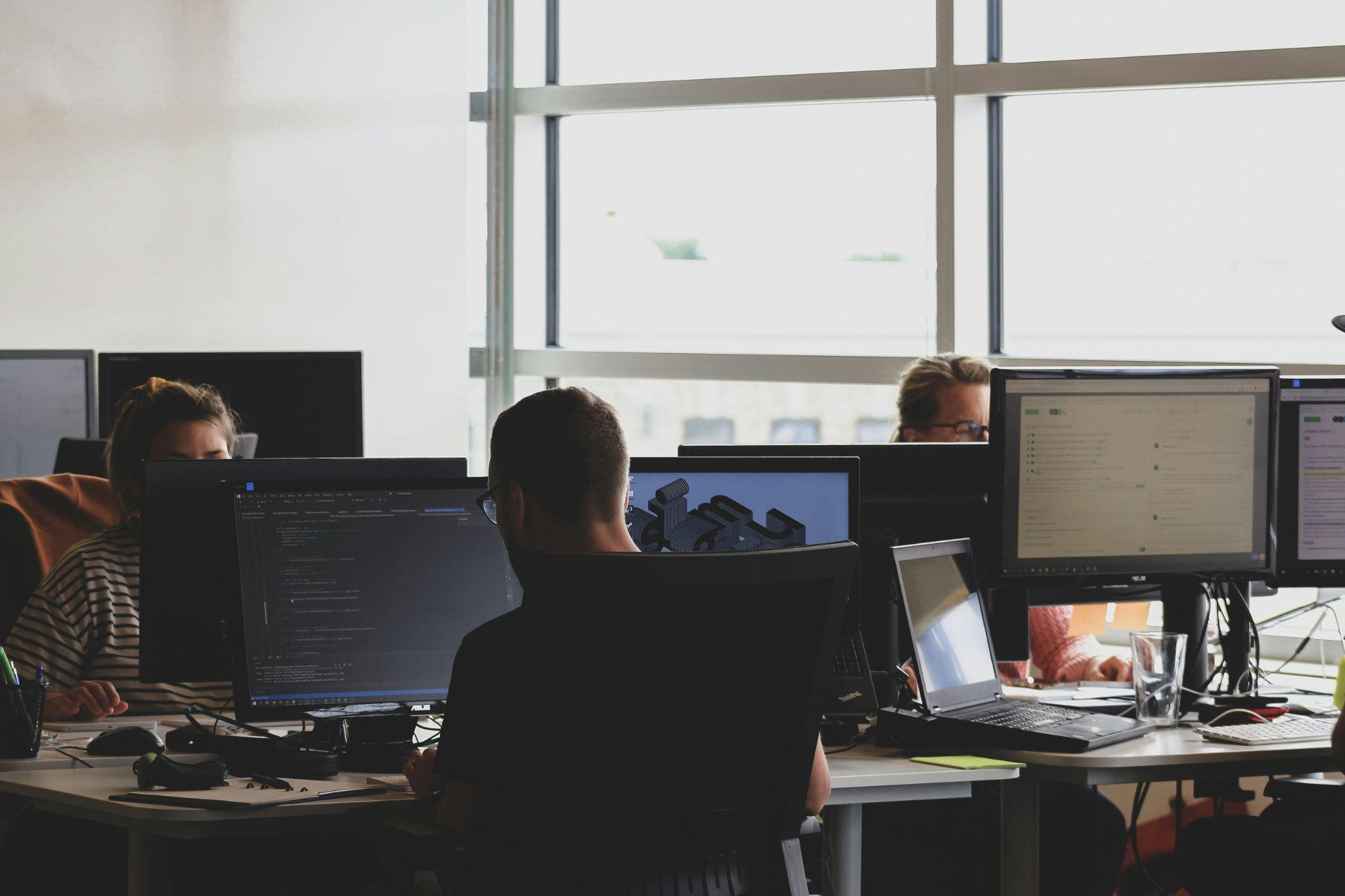 HR professionals in an office setting working on computers, representing the need for phishing scam protection and cybersecurity in HR teams