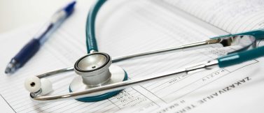 Stethoscope resting on a medical form with a pen nearby, symbolizing health insurance and medical documentation