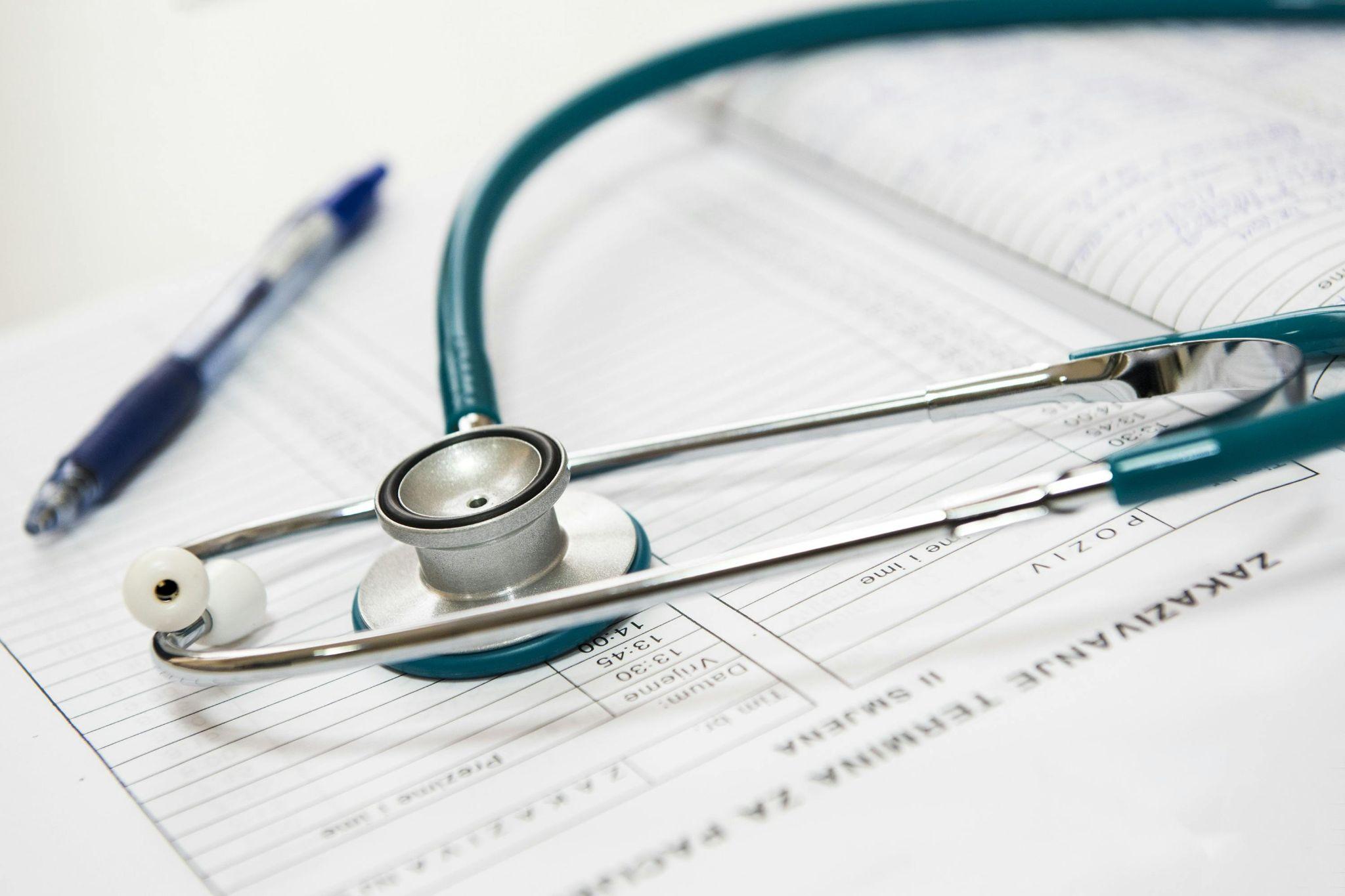 Stethoscope resting on a medical form with a pen nearby, symbolizing health insurance and medical documentation