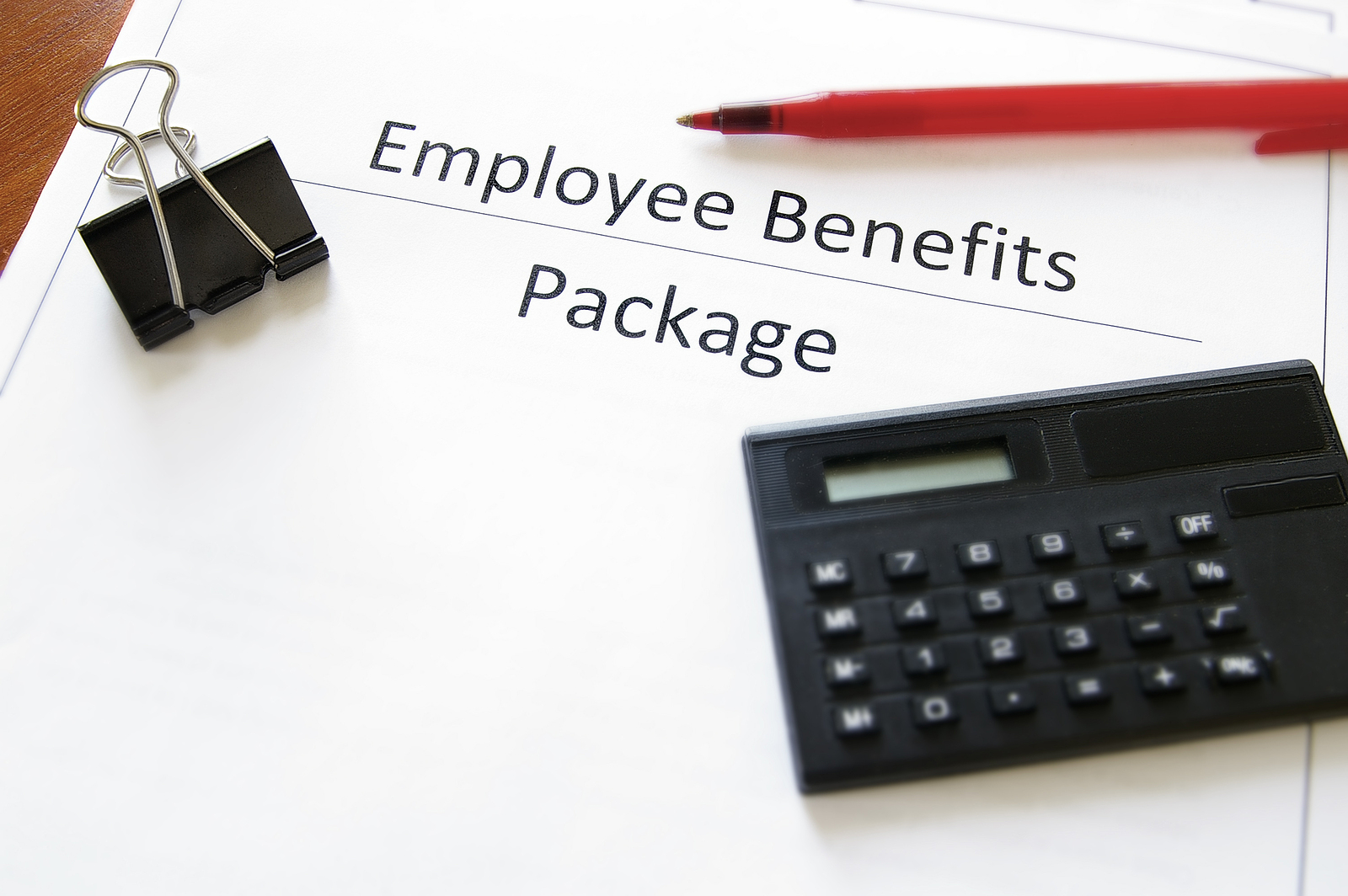 Employee benefits package paperwork with calculator and pen, highlighting annual benefits renewal and employee benefits review process