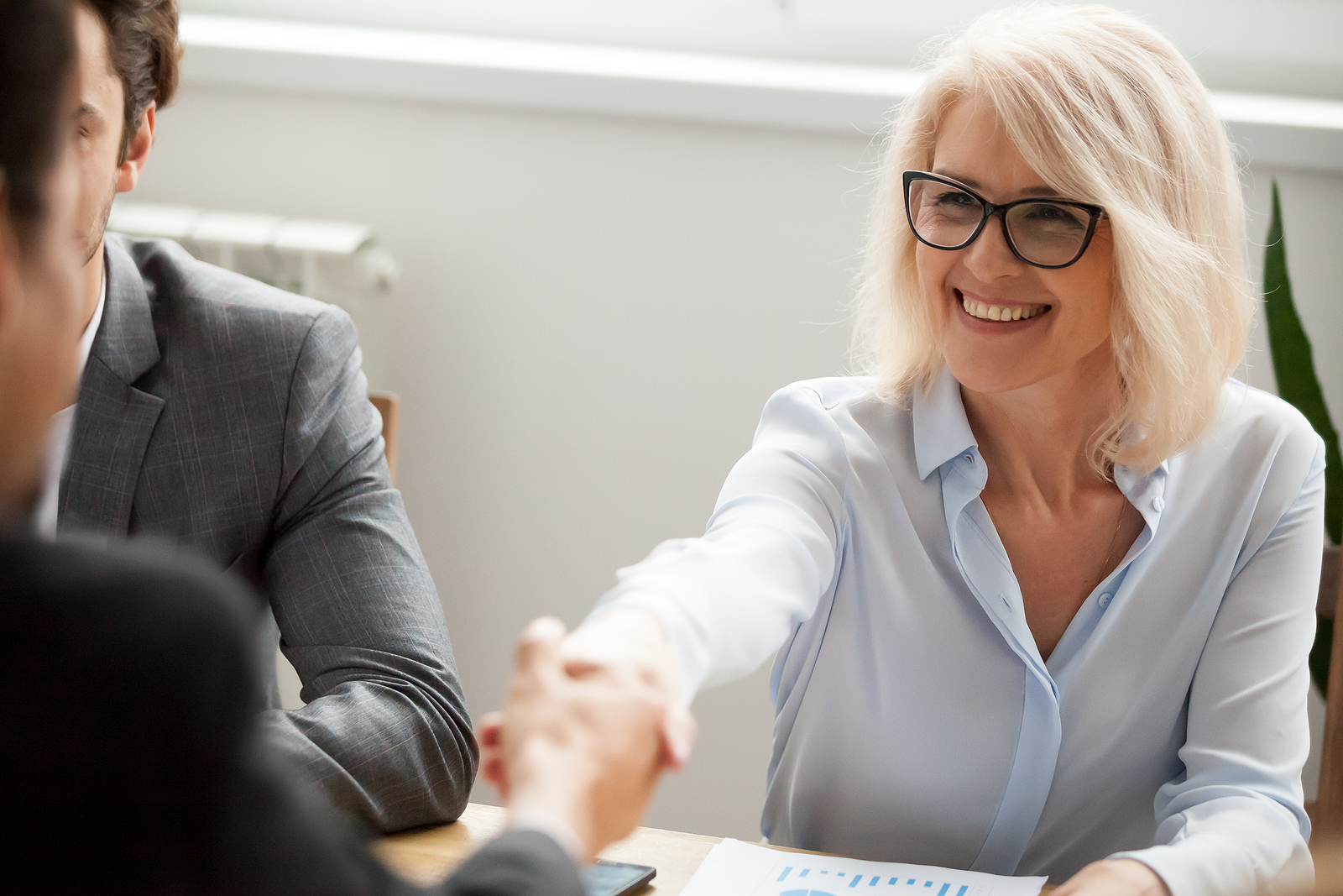 Businesswoman shaking hands during onboarding, highlighting employee training methods and LMS vs traditional training for corporate success.